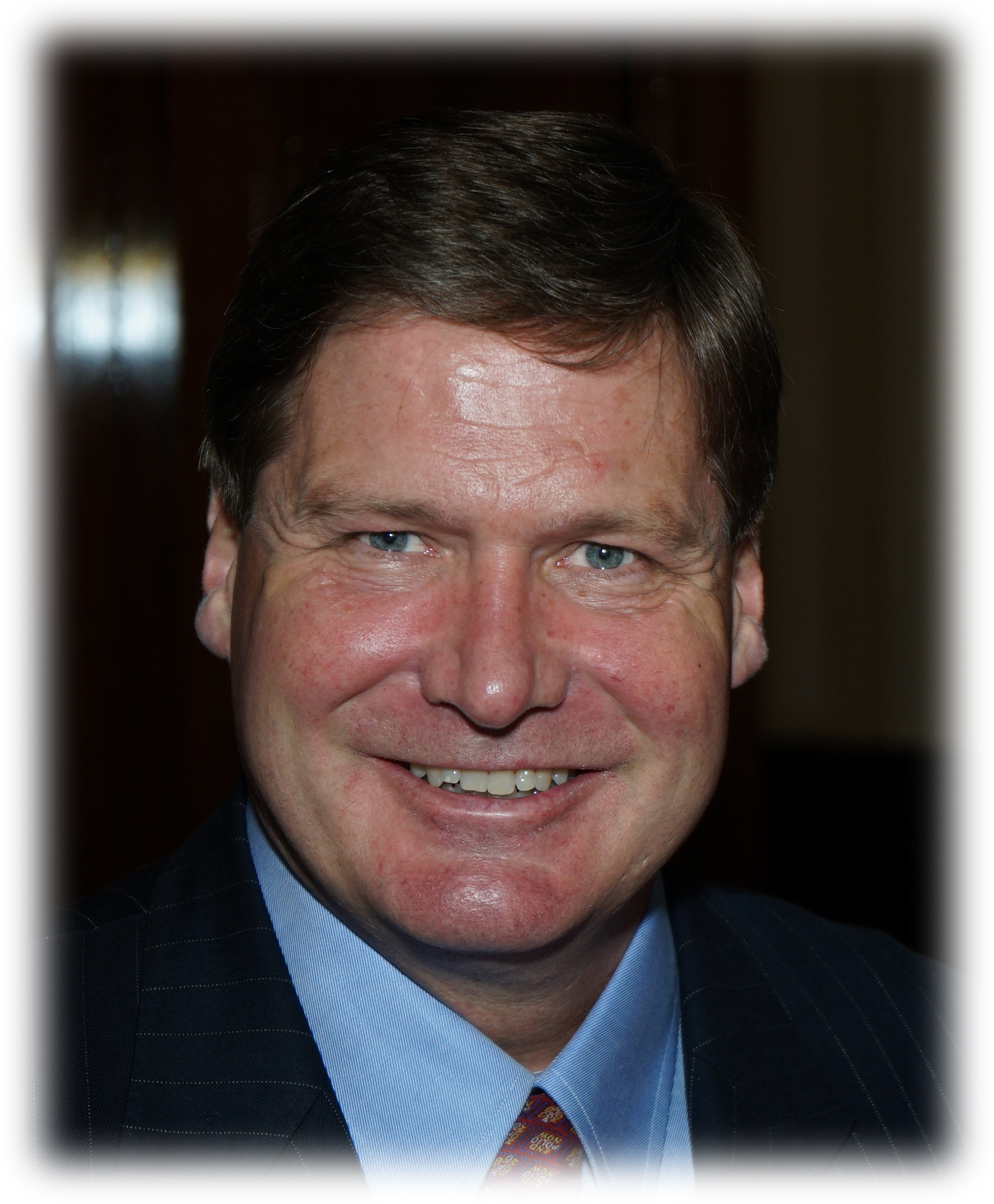 A man in a suit and tie smiling for the camera.